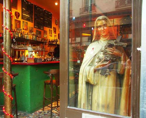 Virgin Bar -- Marais District, Paris -- In the backstreets of the Marais district of Paris there are lots of small bars and bistros.  The Virgin Bar was adorned with many religious icons.  The internet cafe was reflected on Saint Therese who commanded the window of the bar.